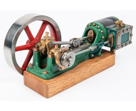 A Stuart single cylinder stationary live steam engine. Horizontal engine with 130mm flywheel. Mounted on oak base and painted