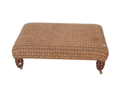A large contemporary upholstered footstool on turned supports with brass casters. H33cm x W102cm x D80cm.
