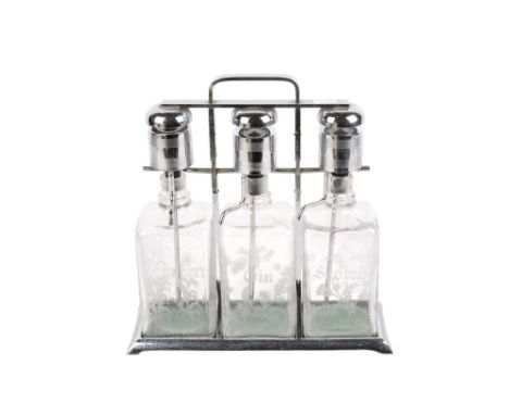 A 20th century tantalus. Comprising three bottles engraved with flowers and marked 'Scotch', 'Gin' and 'Bourbon', within a ch