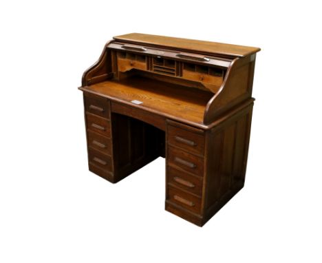 An early 20th century oak tambour front desk. The tambour shutter opening to reveal a fitted interior, over two four drawer p