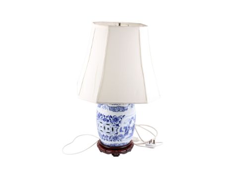 A late 20th century Chinese blue and white ceramic table lamp. Raised on carved wooden base with panels of people in a landsc
