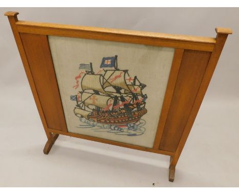 An early 20thC oak Arts and Crafts style fire screen, inset with a crewel work panel of a boat, 54cm wide.