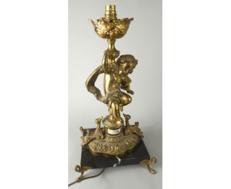 A baroque style table lamp, formed with cherubic stem, floral dish holder and shaped base, on an onyx stand, terminating in h