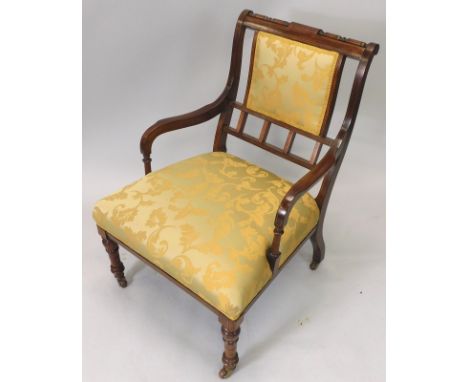 A late Victorian rosewood and boxwood strung armchair, with a padded back and seat, on turned tapering legs with ceramic cast