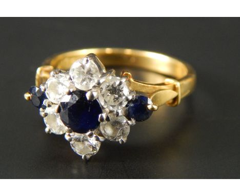 A sapphire and diamond floral cluster ring, with central sapphire surrounded by six diamonds, further flanked by two sapphire