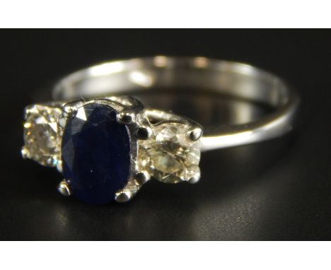 An 18ct white gold sapphire and diamond ring, with central oval cut sapphire, 6.4mm x 4.8mm x 2.8mm, flanked by two round bri