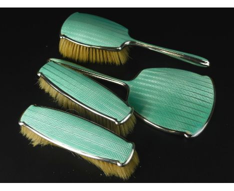 An Art Deco period silver and turquoise guilloche enamel four piece dressing table set, to include three brushes and a mirror