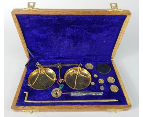 A set of brass scales, weighing up to 50g, in a walnut veneered fitted case.