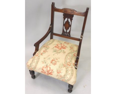 An Edwardian mahogany and marquetry low armchair, with a padded seat, on turned legs with ceramic castors.