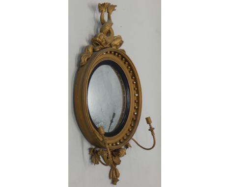 A Regency giltwood and gesso convex girandole, with an intertwined dolphin crest, a reeded slip and two candle arms, 97cm hig
