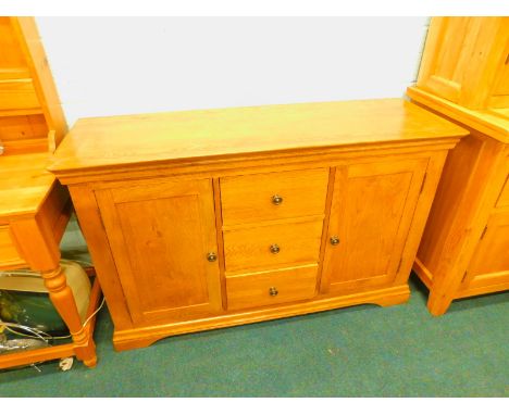 An oak sideboard, with three drawers flanked by two panelled doors, on bracket feet, 136cm wide.