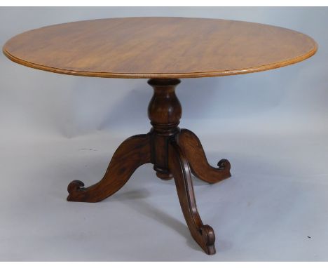 A circular oak dining table, the top with a moulded edge on turned column and tripod base, 130cm dia.