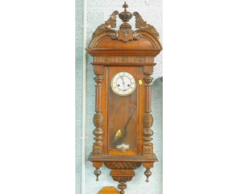 A Vienna type walnut wall clock, with a shaped crest, the white enamel dial with Roman numerals (AF), 115cm high
