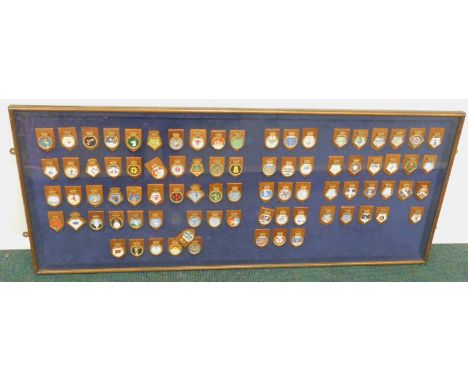 A framed collection of around 80 miniature models of ship's badges, made by a former serving officer on HMS Invincible during