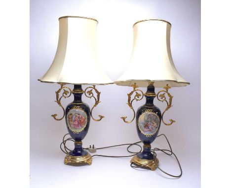 A pair of Continental ceramic and gilt metal mounted table lamps, each with central oval panel illustrating trios of figures 