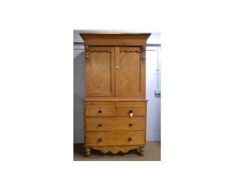 A Victorian stripped pine press, the tapered cornice above a pair of panel doors with leaf pattern corbels, opening to reveal