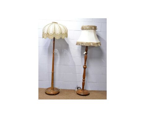 A mid Century turned oak lamp standard with shade, 179cms high; a mid Century beechwood lamp standard with tasselled shade, 1