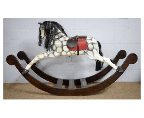 A vintage hand-carved wooden dapple-grey rocking horse, with black mane, leather saddle and bowed rocker, 174 x 43 x 102cms a