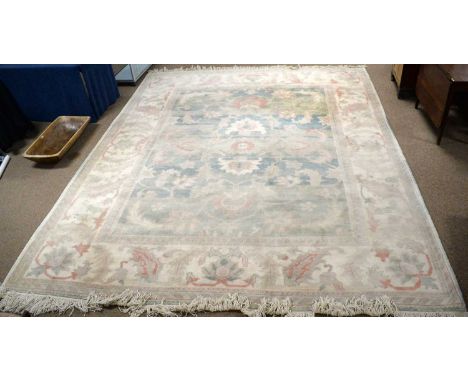 A modern Persian style carpet, the cream, blue and green central panel with allover foliate design, palmette and leaf border,