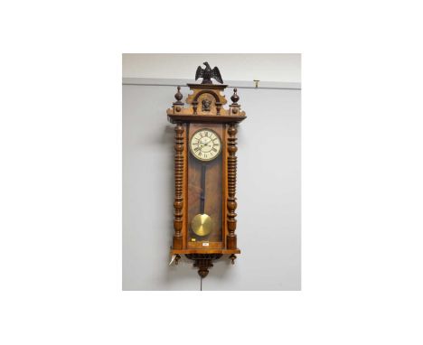 A Viennese stained beechwood wall clock, with eagle finial, mask and turned frieze, enamelled roman dial with subsidiary seco