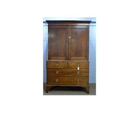 A Georgian oak press, the cavetto cornice above a pair of panel doors enclosing a shelved interior, the lower section with tw