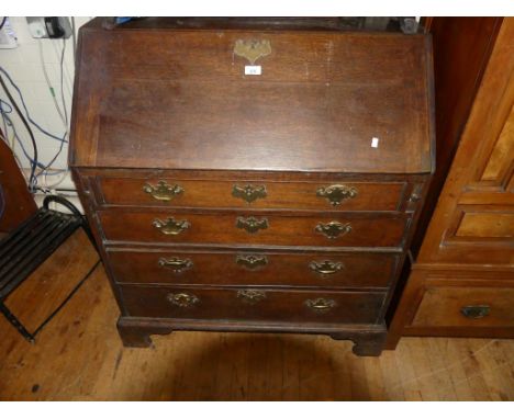 An 18th Century oak bureau of typical form, the fall front opening to an interior of pigeon holes and small drawers over a fo