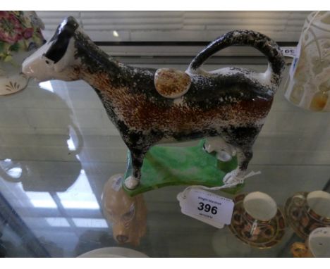 A Staffordshire spongeware cow creamerModelled in the form of a standing cow being milked, raised green plinth base, length 1