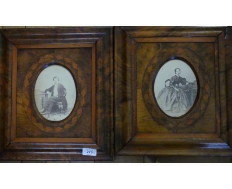 A pair of late Victorian walnut frames with oval apertures containing vintage portrait photos of a lady and gent 