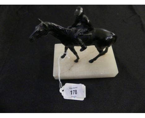 A small bronzed spelter model of racehorse and jockeySet on a polished onyx plinth base, unsigned, height 13cm 