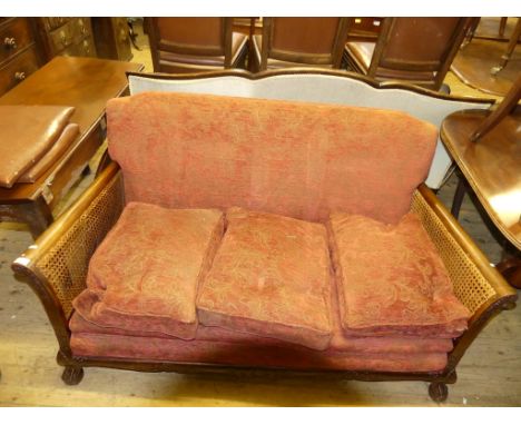 An Edwardian bergere sofa with red upholstered loose cushions, raised on paw feet 