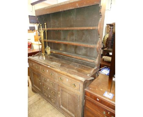 A George III oak dresser with three shelf back over a base with three drawers, three dummy drawers and two doors, raised on b