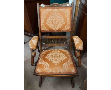 An early 20th Century stained wood framed folding elbow chair with machine tapestry upholstery