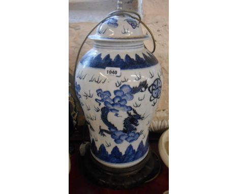 A large 20th Century porcelain table lamp of lidded temple jar form with hand painted dragon decoration, set on carved hardwo