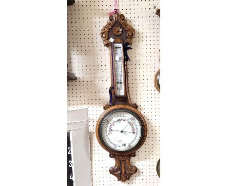 A late Victorian ornate carved and stained oak banjo barometer/thermometer with printed dial and scale - a/f