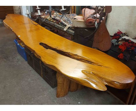 A 3m Indonesian hardwood bench with shaped, polished and part pierced natural plank top, set on flanking rustic standard ends