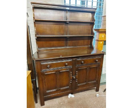 A 1.22m vintage Ercol dark elm two part dresser with two shelf open plate rack over a base with two frieze drawers and panell