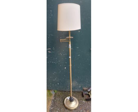 A modern brassed metal reading standard lamp with adjustable top and shade