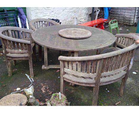 A large circular teak garden table - sold with a curved bench and two chairs