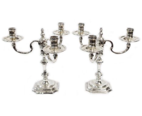 A pair of 22cm high cast silver three branch table candelabra with removable top sections for single candle use, set on stepp