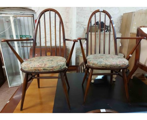 A pair of vintage Ercol dark elm hoop stick back carver chairs, set on tapered supports