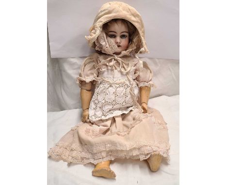 A 19th Century German porcelain headed doll with composition body, glass eyes and original clothing