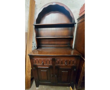 A 94cm vintage dark stained elm Ercol style two part dresser with arched two shelf open plate rack over a base with two friez