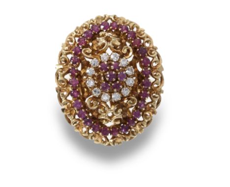 A ruby and diamond dress ring, the oval raised scrolled 18 carat gold openwork design set to centre with a cluster of circula