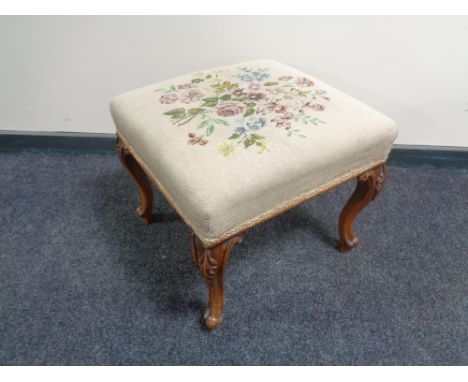An antique tapestry footstool on cabriole legs 