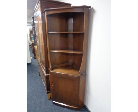 An Ercol elm corner cabinet fitted with shelves 