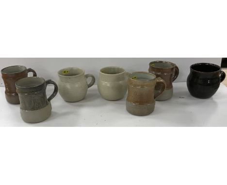 A collection of various Winchcombe Pottery mugs including four with wavy line and leaf type decoration, two cream glazed and 