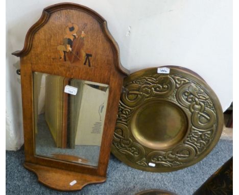 An oak framed bevel edged wall mirror with a bottom shelf and inlay of a cello player together with a brass plaque and oval p