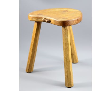 MOUSEMAN; a Robert Thompson oak stool with shaped seat raised on three octagonal supports, height 36cm.