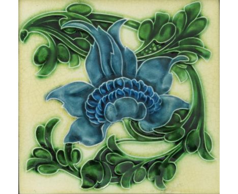 A Pilkington's Lancastrian tile designed by Lewis F Day, modelled in low relief with a flower design in green and blue on a c