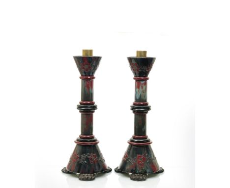 A tall pair of Sunflower Pottery candlesticks by Sir Edmund Elton, each on three claw feet, with tapering cylindrical base an